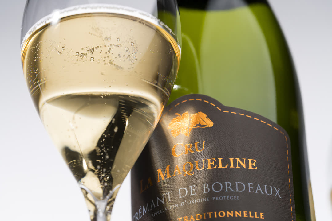 Flûte de Crémant de Bordeaux devant une bouteille de Cru La Maqueline